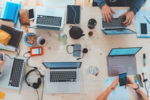 A table of social media marketers work at their laptops